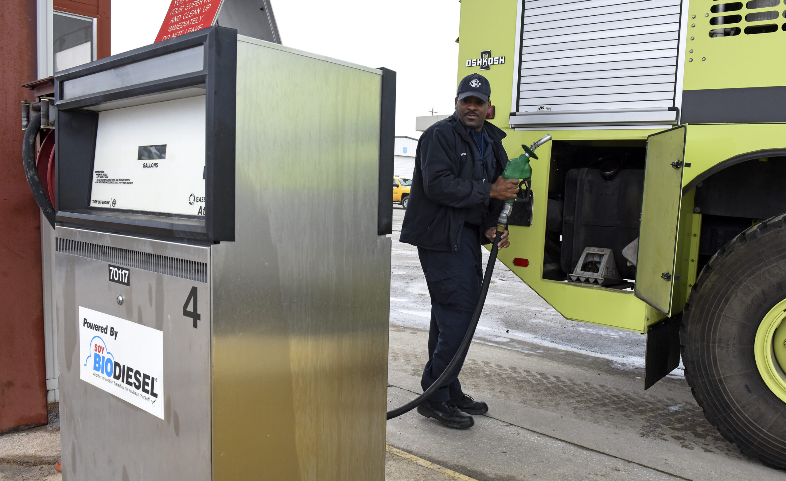 Man holding biodiesel gas pump in front of a vehicle