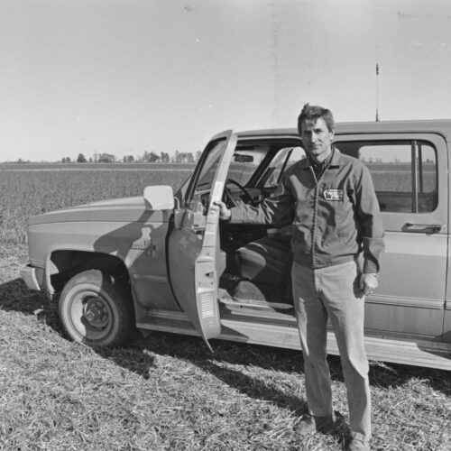 Man Standing In Front Of Car And Field
