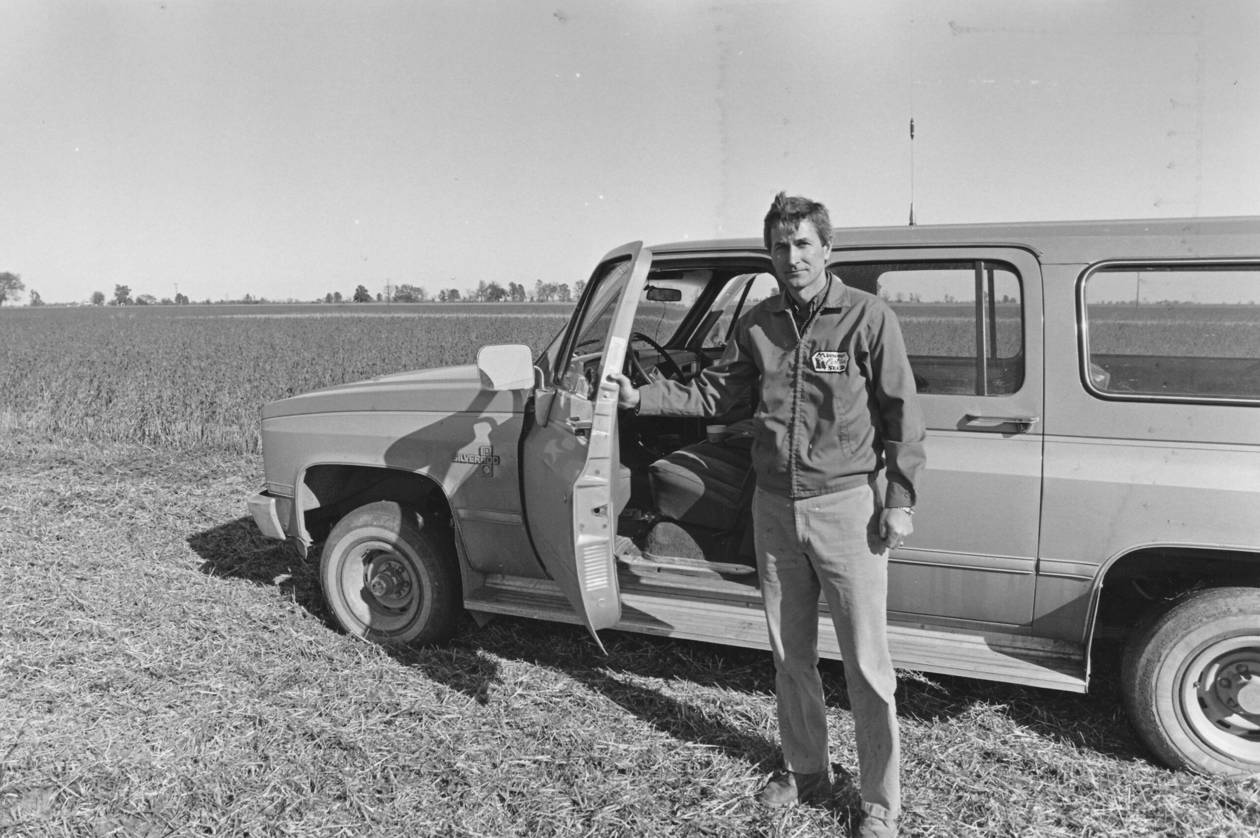 Man standing in front of car and field