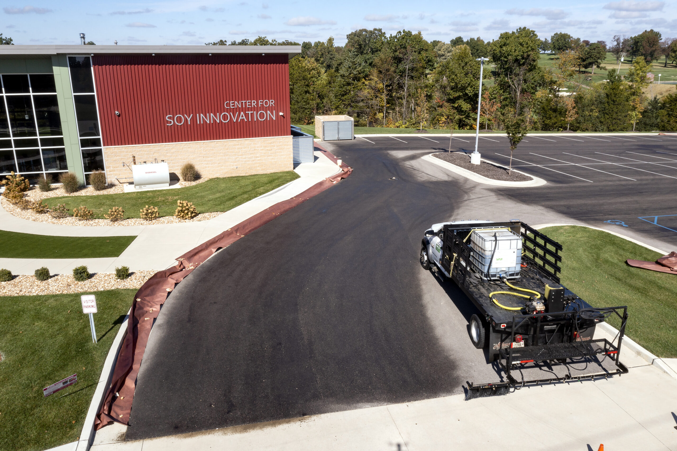 A truck applying RePlay is an agricultural oil seal and preservation agent to the asphalt in front of the Center for Soy Innovation Building
