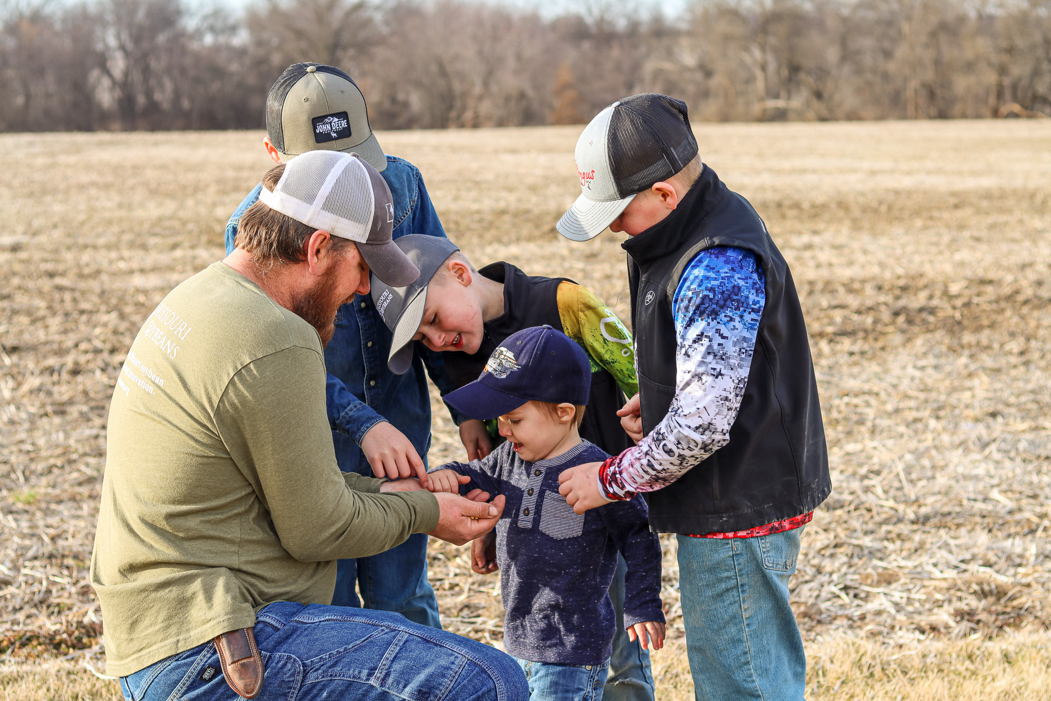 Farmer and sons looking at soy in harvested field